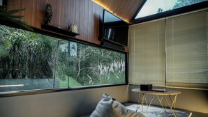 Ein modernes Zimmer mit einem großen Fenster, einem Sitzsack, einem kleinen Tisch und einem Fernseher.
