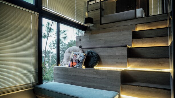 Ein modernes Interieur mit einer eingebauten Bank, Holzwegen und Blick auf Grün.
