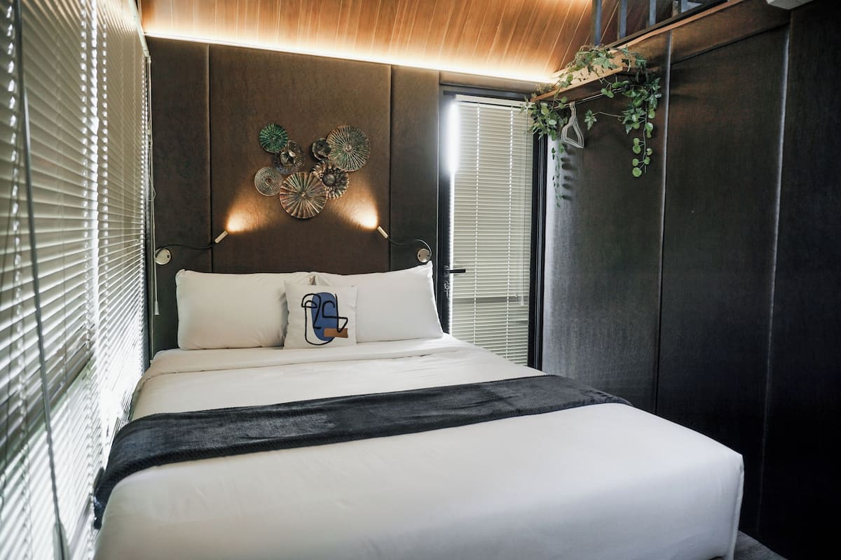 Un dormitorio moderno con una cama grande, una pieza decorativa sobre la cama y una planta colgante.