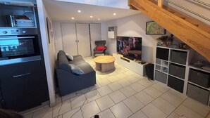 Ein modernes Wohnzimmer mit einer Couch, einem Couchtisch, einem Fernseher und einer Treppe.