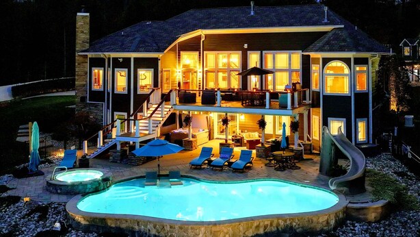 Ein zweistöckiges Haus mit Swimmingpool, Sitzgelegenheiten im Freien und einer Rutsche.