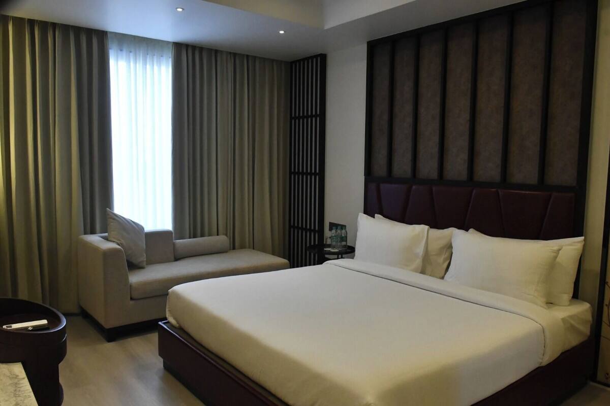 A hotel room with a large bed, a sofa, and a nightstand.