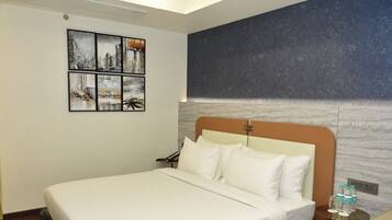 A hotel room with a large bed, a headboard with a marble-like texture, and a wall-mounted artwork depicting cityscapes.