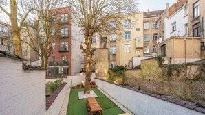 A courtyard with a wooden table and benches, surrounded by buildings with balconies and windows. - Room-euro Edens Cosy Historic Home in Br (Brussels)