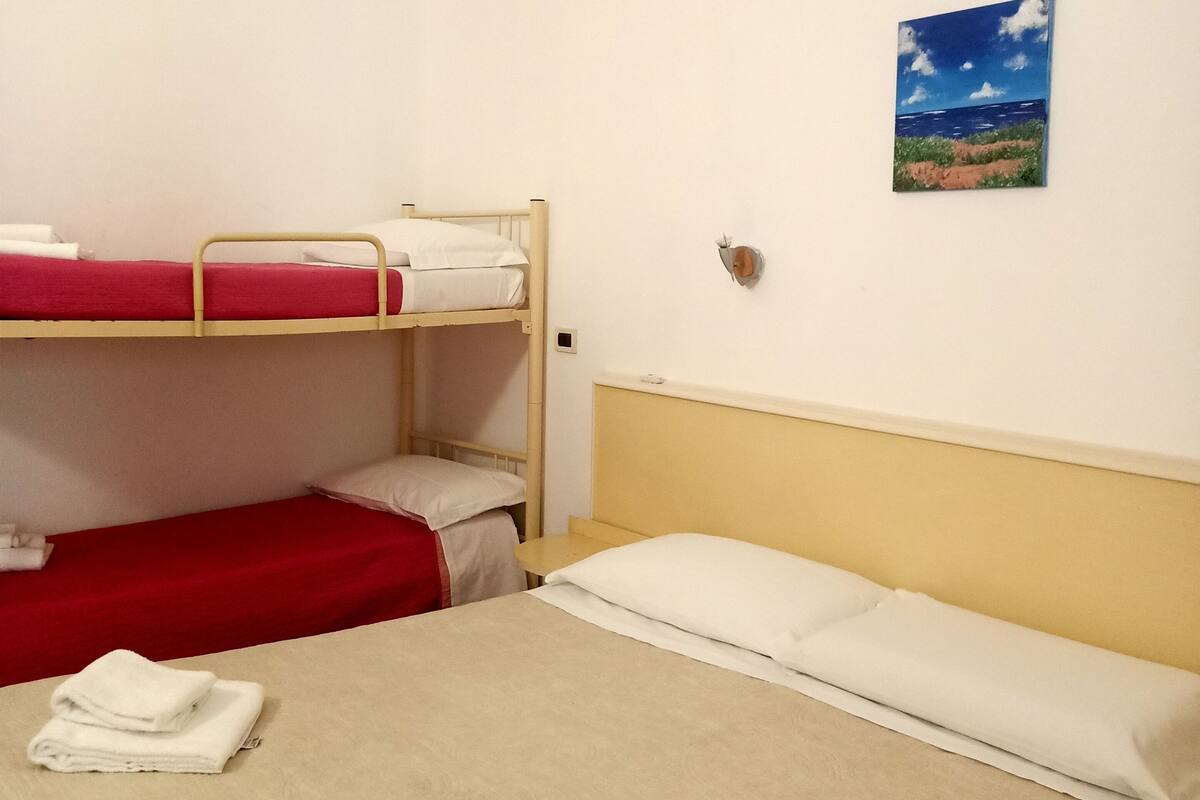 Una habitación con literas, una cama individual y un cuadro colgado en la pared.