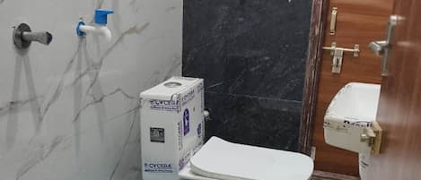 Un bagno piccolo con un WC, un secchio blu e una scatola con l'etichetta 'CYCERA'.
