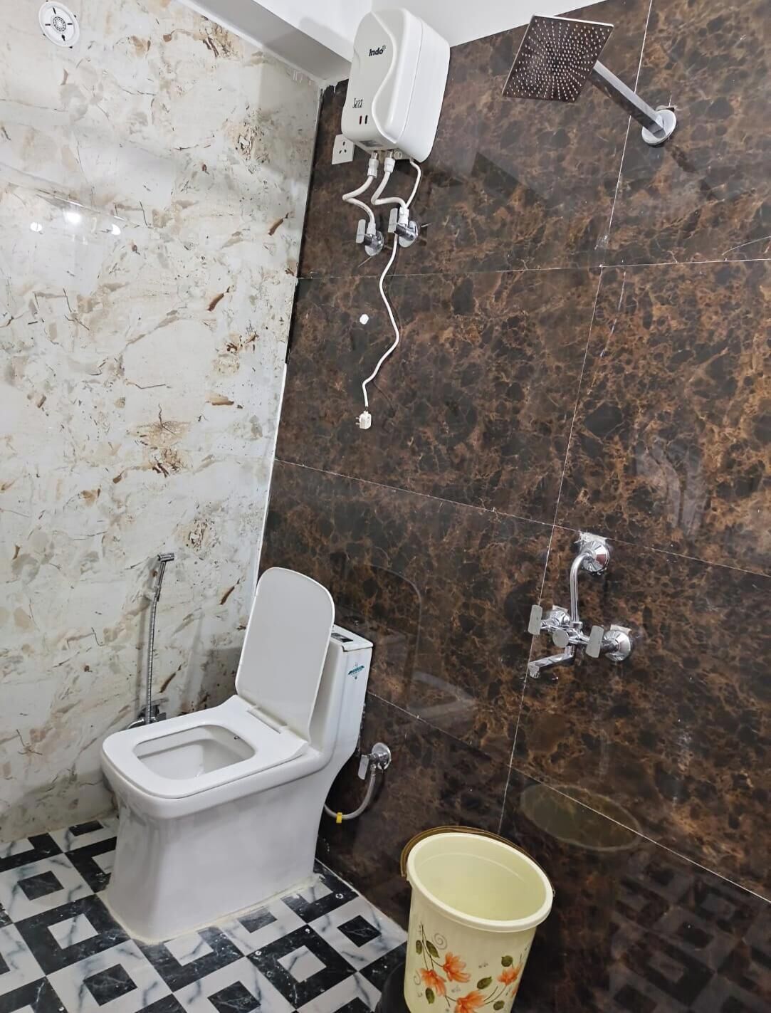 A bathroom with a toilet, a shower, and a marble wall.