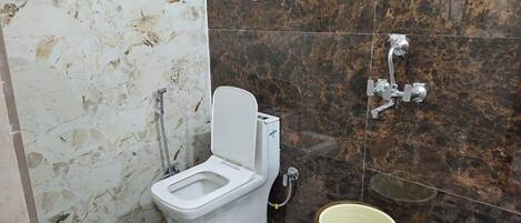 Un baño con inodoro, ducha y un balde.