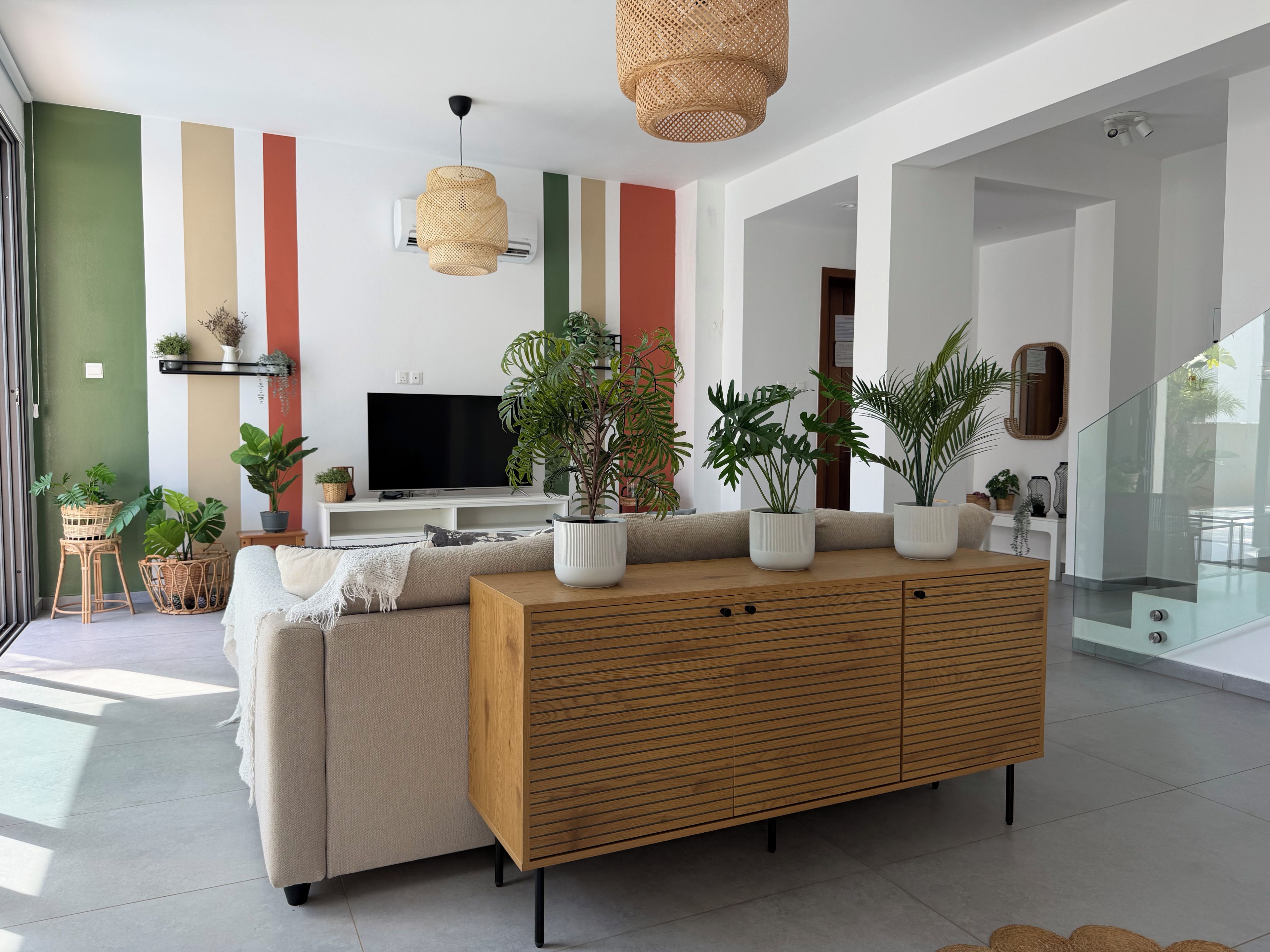 Uma sala de estar moderna com sofá, armário de madeira e plantas em vasos.