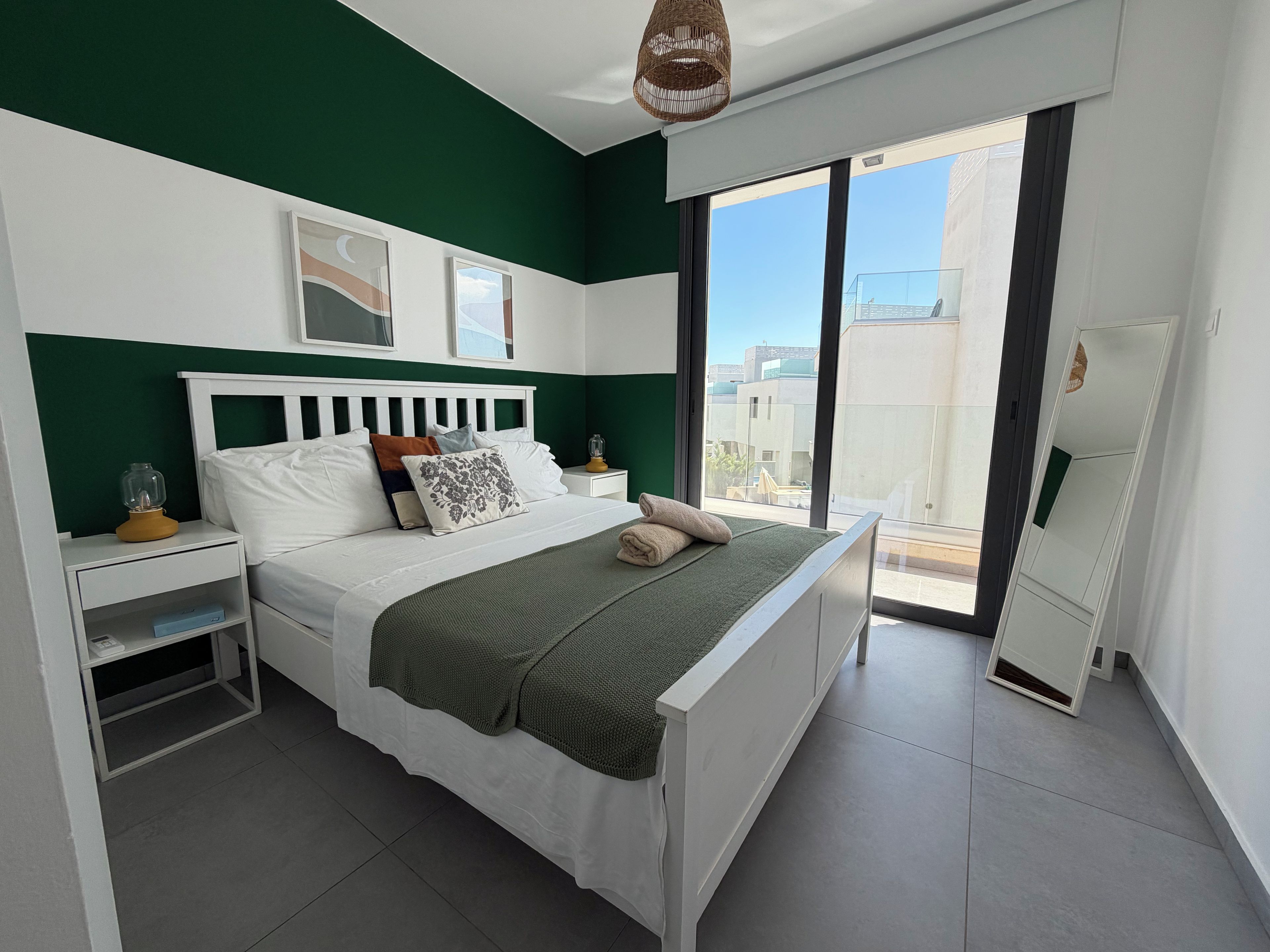 Un dormitorio moderno con cama, mesitas de noche y vistas al exterior.
