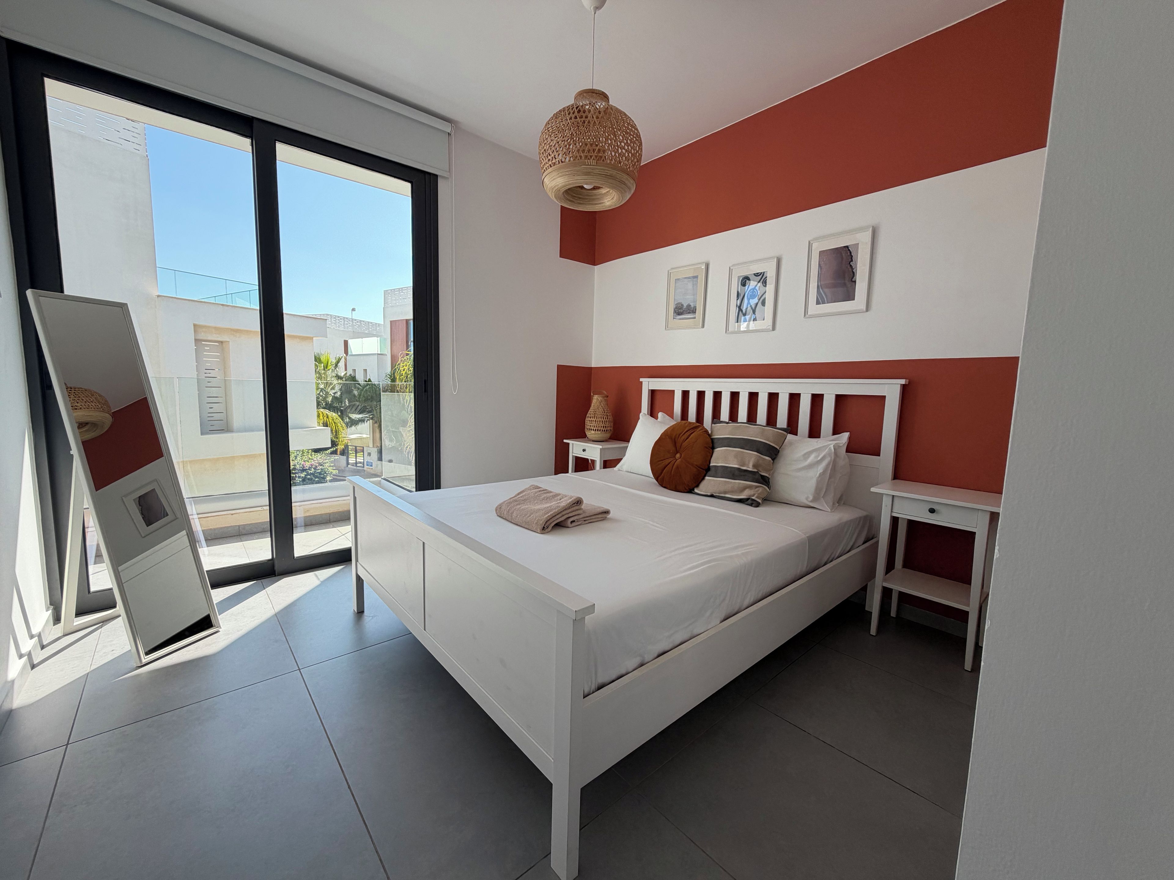 A modern bedroom with a bed, bedside tables, and a view of the outside.
