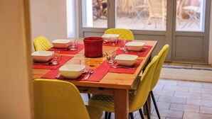 A dining table set with bowls, glasses, and cutlery, surrounded by yellow chairs. - Le Fare d'Emilie - Polynesian stopover (Gaillac)
