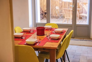 A dining table set with bowls, glasses, and cutlery, surrounded by yellow chairs. - Le Fare d'Emilie - Polynesian stopover (Gaillac)