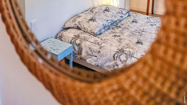 A room with a bed, a small table, a lamp, and a wall with a palm tree mural. - Le Fare d'Emilie - Polynesian stopover (Gaillac)