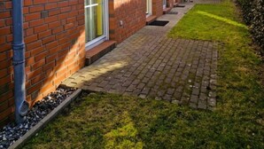Una casa in mattoni con un vialetto lastricato e un piccolo giardino.