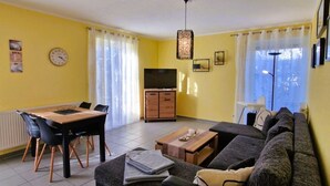 Un soggiorno con divano, tavolo da pranzo con sedie, televisione e un armadio.