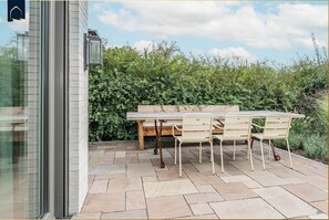 An outdoor patio with a wooden table and chairs, a bench, and a hedge in the background. - Modern vacation home with sauna, parking & close to the beach - Ückeritz (Ückeritz)