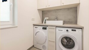 Un espace buanderie compact comprenant un lave-linge, un sèche-linge et un petit évier.