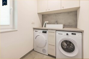 A compact laundry area with a washing machine, dryer, and a small sink. - Modern vacation home with sauna, parking & close to the beach - Ückeritz (Ückeritz)