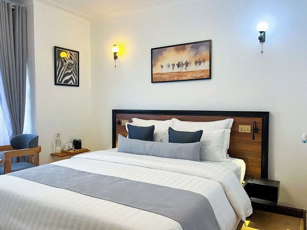A hotel room with a large bed, two wall-mounted lights, a painting of a zebra, and a painting of a herd of cattle. - SKA The Boutique Naguru (Kampala)