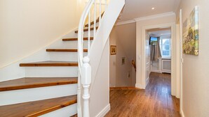 A staircase with wooden steps and white balusters leading to a hallway with wooden flooring and a door at the end. - Senhuk - Senhuk part of the vacation home. With garden and terrace for up to 6 people. (Sylt)