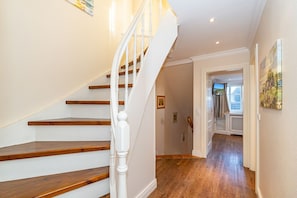 A staircase with wooden steps and white balusters leading to a hallway with wooden flooring and a door at the end. - Senhuk - Senhuk part of the vacation home. With garden and terrace for up to 6 people. (Sylt)