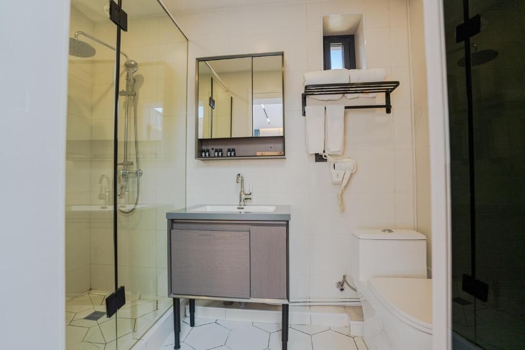 A modern bathroom with a glass-enclosed shower, a sink with a mirror, and a toilet.