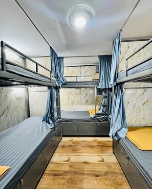 A bunk room with two beds, a wooden floor, and marble-patterned walls. - Blue Top Dormitory (Mumbai)