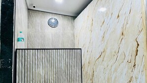 A modern interior with a marble wall, a clock, and a bottle of water on the wall. - Blue Top Dormitory (Mumbai)