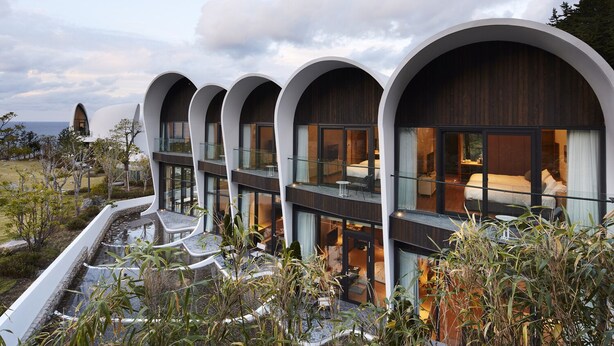 Un hotel moderno con arquitectura curvilínea, ventanas amplias y vistas al mar.
