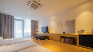 Habitación de hotel con una cama grande, un escritorio con silla, televisión y minibar.