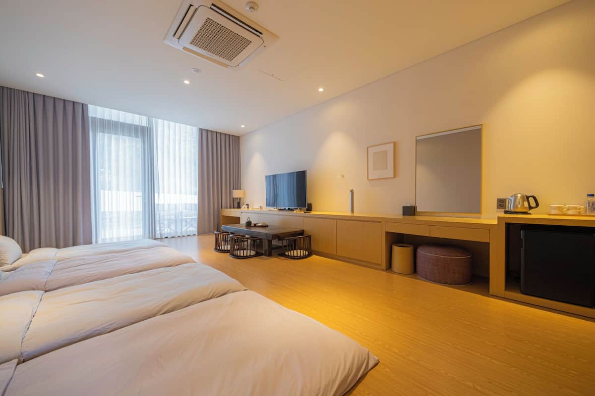 Habitación de hotel con una cama grande, un escritorio con silla, televisión y minibar.