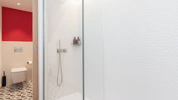 Et stilfuldt badeværelse med brusekabine i glas, toilet og håndvask.