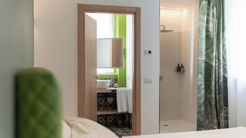 Una habitación de hotel con una cama, un baño con ducha y una pared de acento verde.