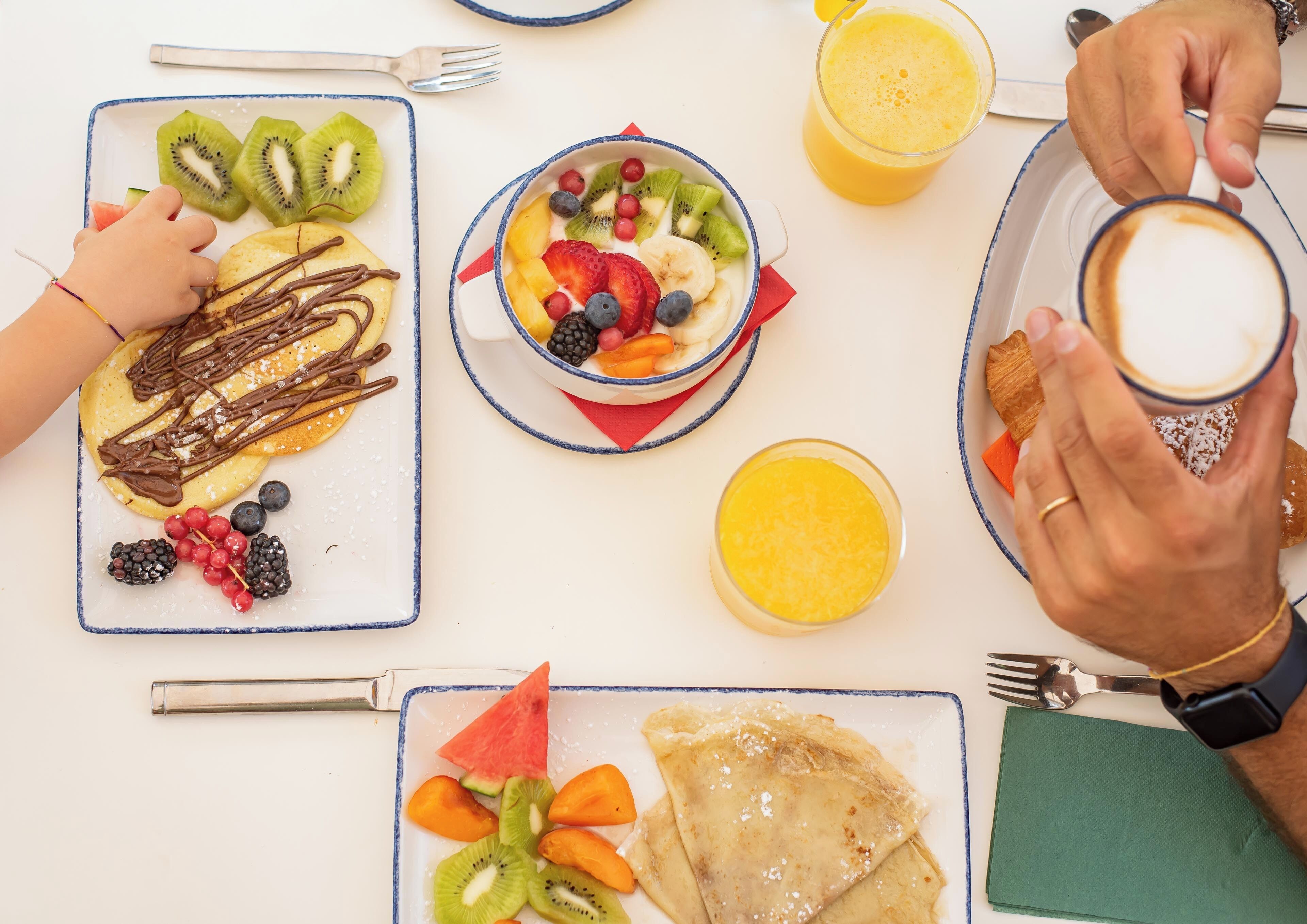 A breakfast setting with pancakes, fruit, and coffee.