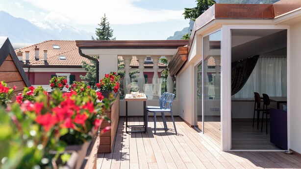 A balcony with a table and chairs, a wooden deck, and a view of mountains in the background. - Lillil Popping Holiday (Riva del Garda)