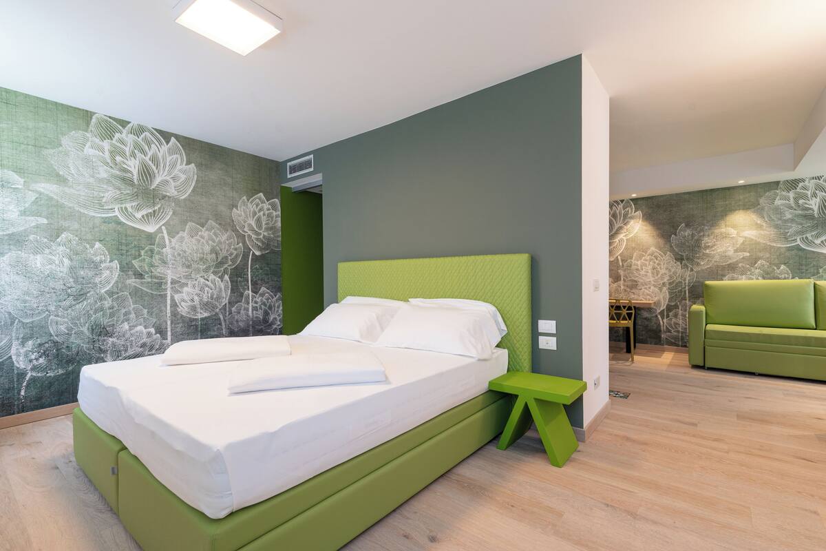 Una camera da letto moderna con un letto, un comodino e una panca, tutto in verde.