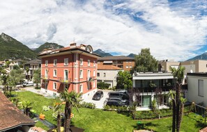 Un edificio a più piani con facciata rossa, un'area di parcheggio con auto e un prato ben curato.