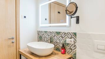 A bathroom with a white sink, a mirror, and a patterned tile backsplash.