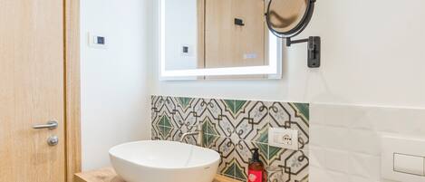 A bathroom with a white sink, a mirror, and a patterned tile backsplash.