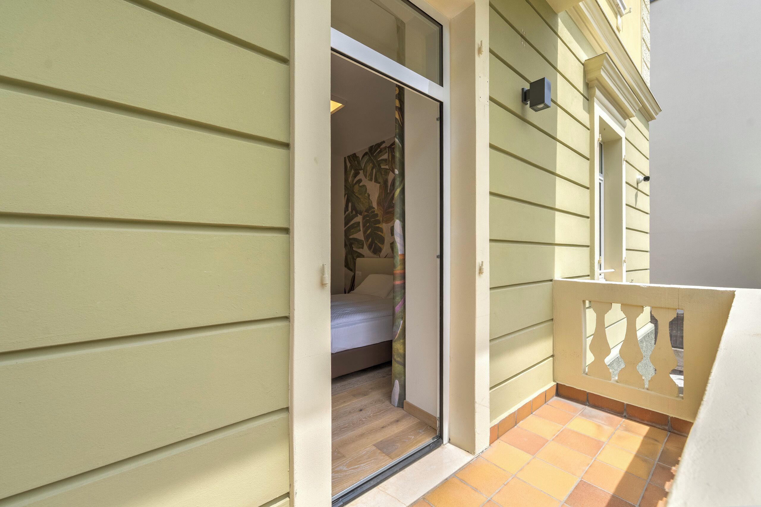 A room with a sliding door leading to a bedroom with a bed and a window.