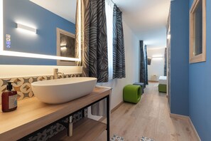 Un bagno moderno con un ampio lavandino bianco, uno specchio e tende a fantasia.
