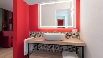 A modern bathroom with a large mirror, a white sink, and a geometric patterned wall.