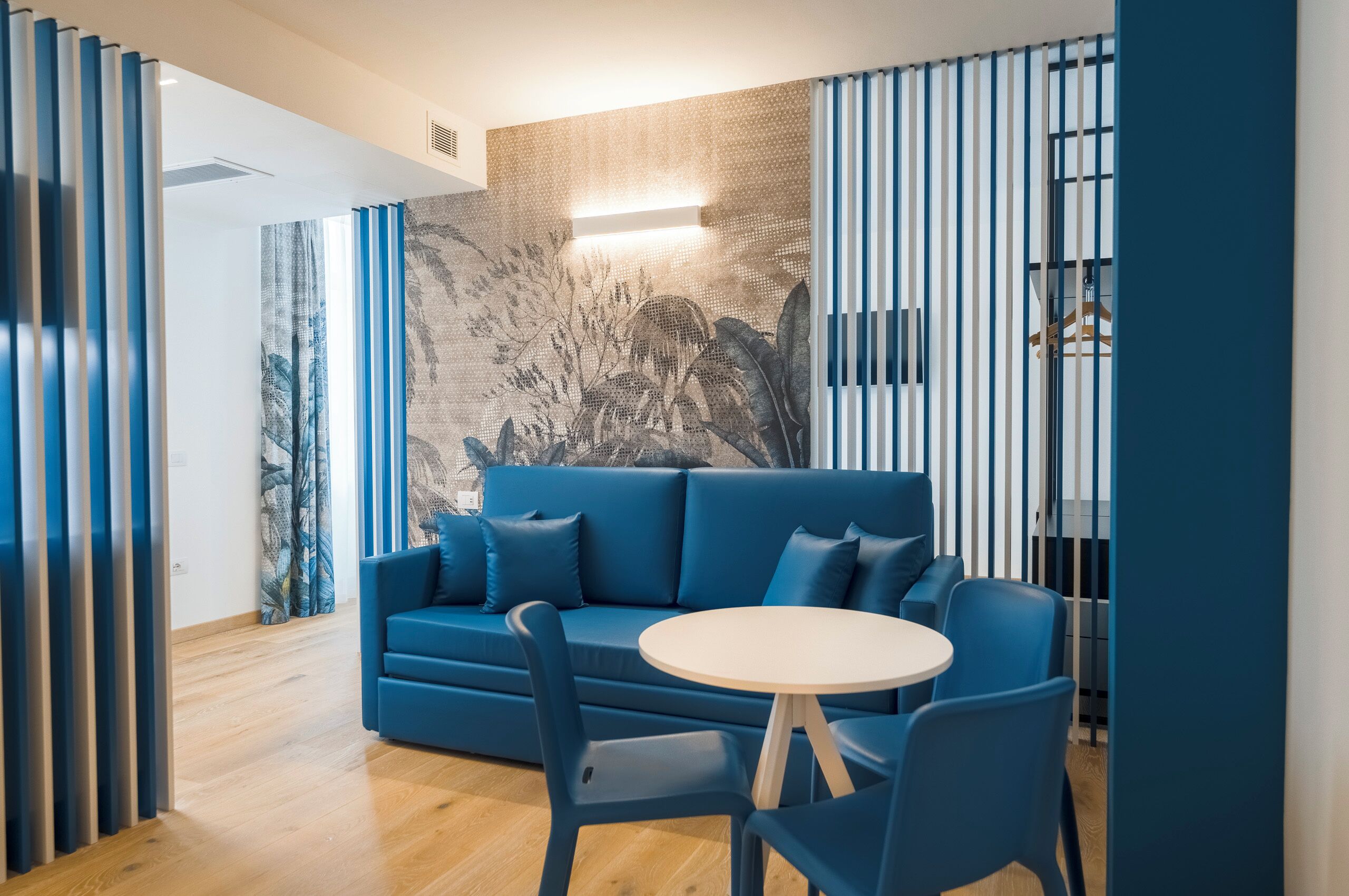 Een moderne woonkamer met een blauwe bank, een ronde tafel en stoelen.