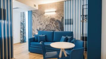 Een moderne woonkamer met een blauwe bank, een ronde tafel en stoelen.