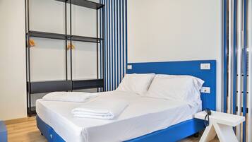 A modern hotel room with a bed, a bedside table, a wardrobe, and a blue accent wall.