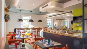 A modern cafe with multiple tables and chairs, a central bar area, and various seating options. - Lillil Popping Holiday (Riva del Garda)