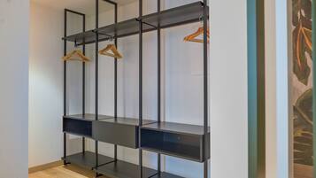 A modern, minimalist closet with black metal shelving and wooden hangers.