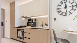 Eine moderne Küche mit Einbauofen, Kaffeemaschine und Wanduhr.