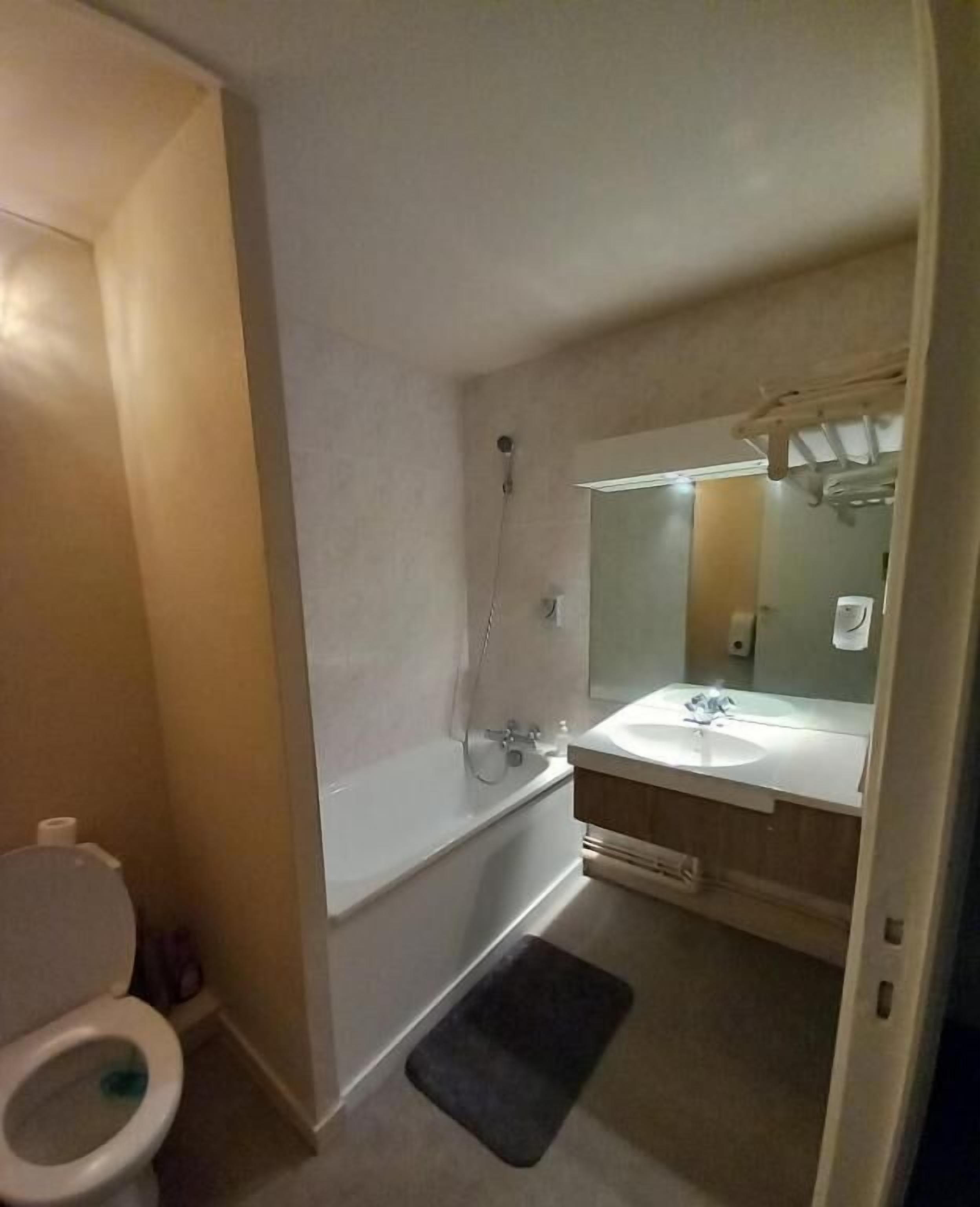 A bathroom with a toilet, a bathtub, a sink, and a mirror.